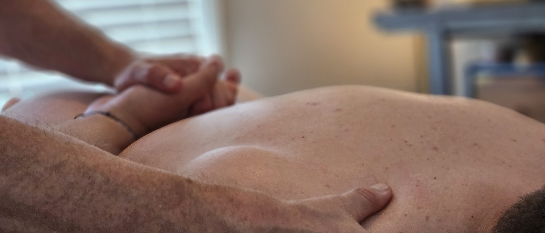 Hands resting along a client's shoulder and back during a session