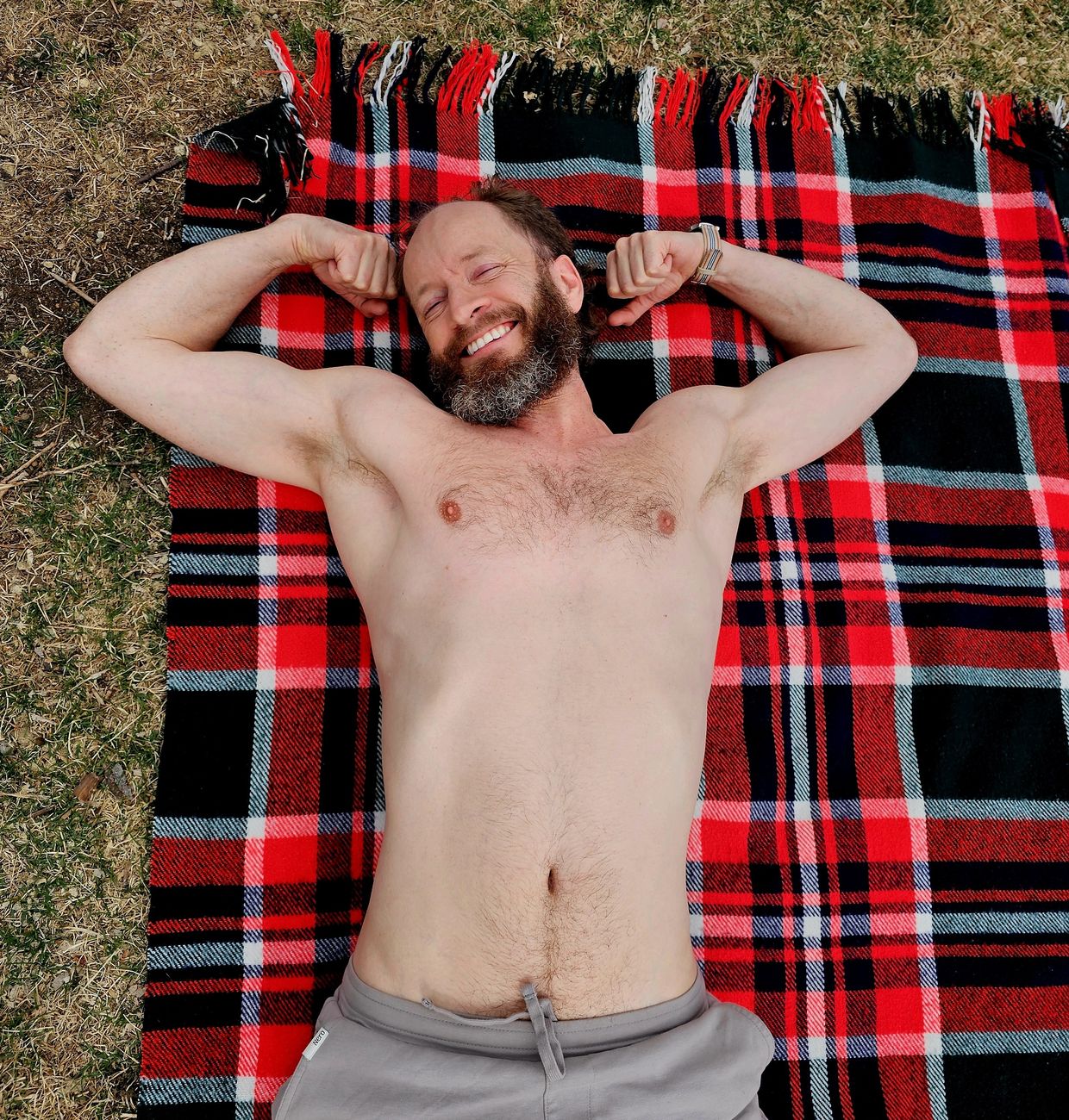 Courage lying on a plaid blanket in the grass, eyes closed, laughing